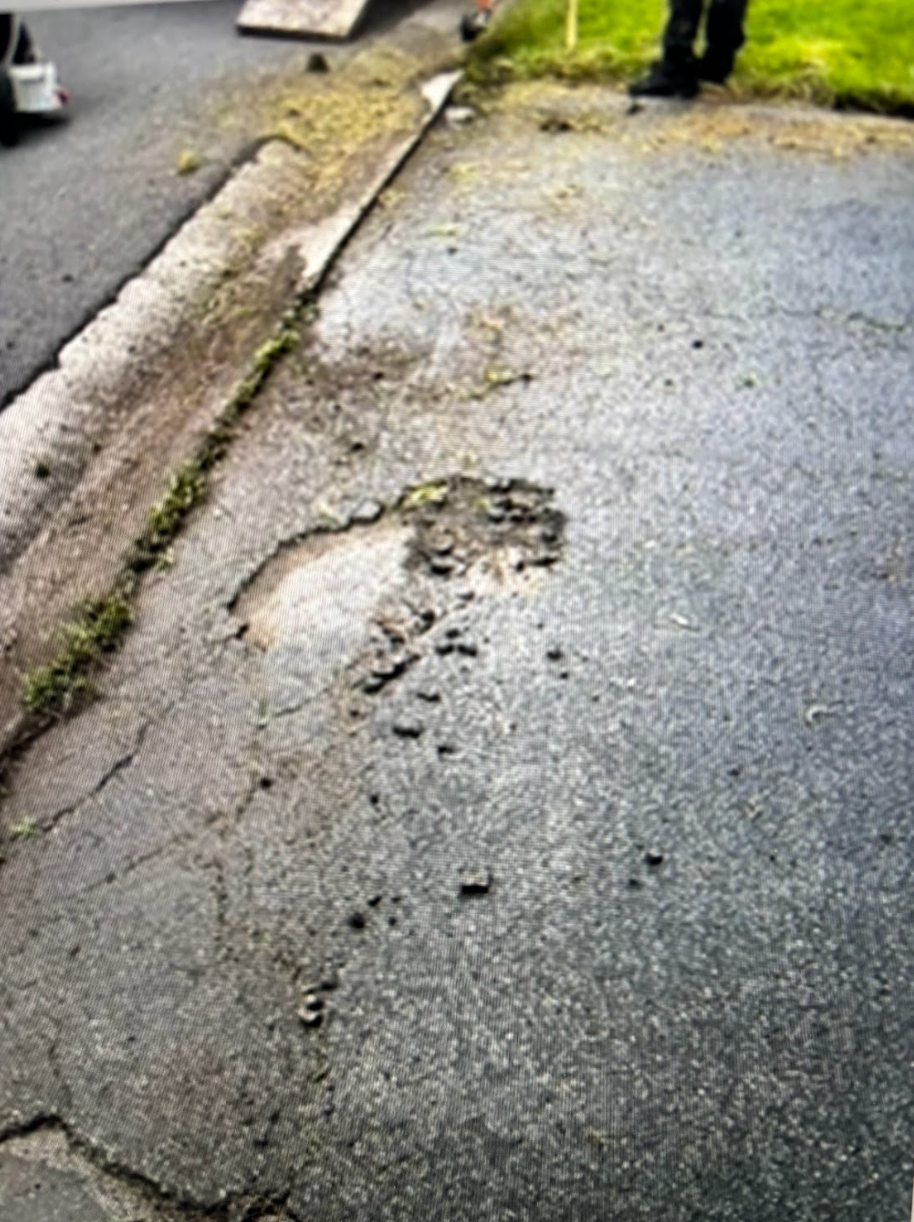 A person is standing next to a hole in the road