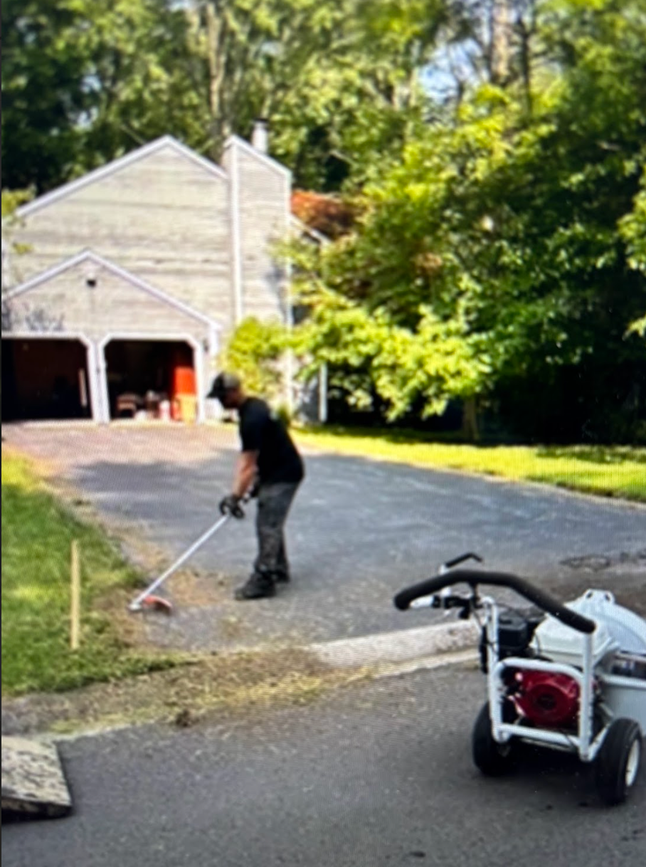 A man is sweeping the grass in front of a house