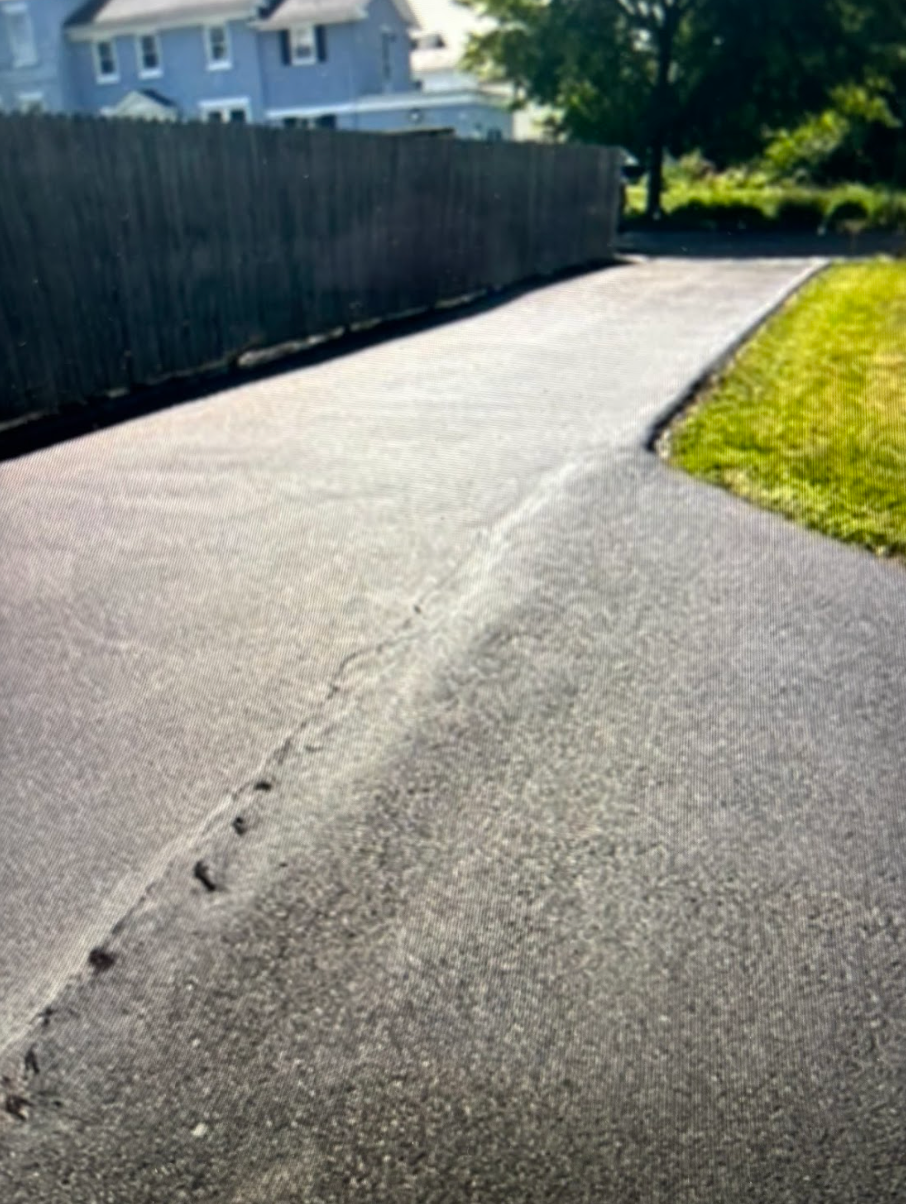 A road with a fence and a house in the background
