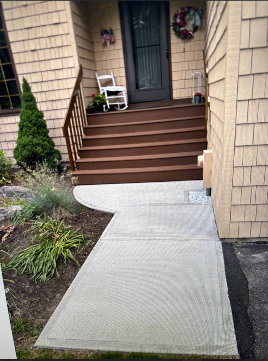 A concrete walkway leading to the front door of a house.