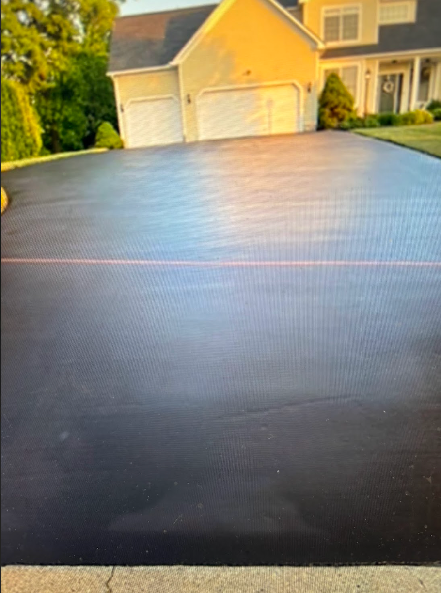 A black driveway with a yellow house in the background