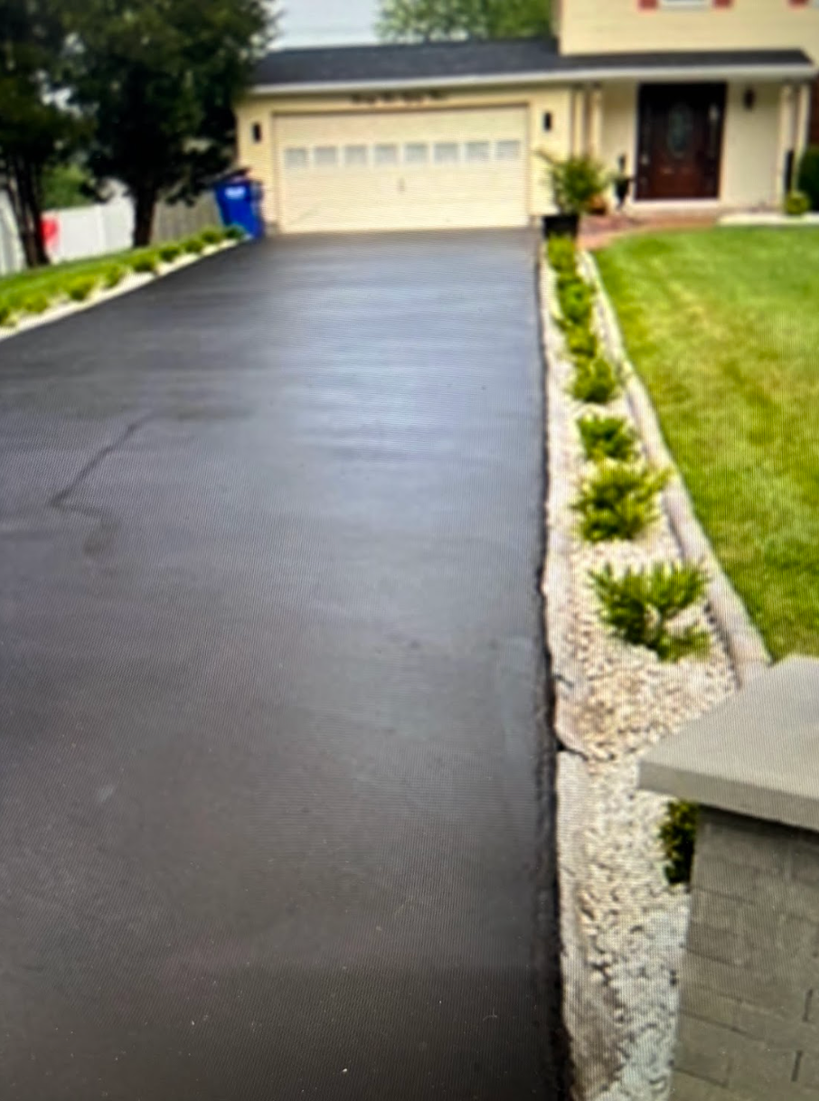 A black driveway leading to a house with a white garage door.