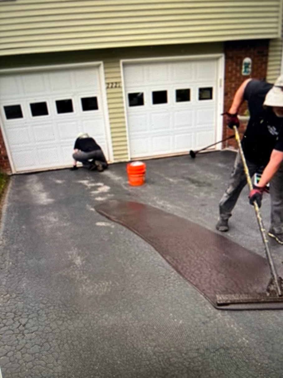 Two men are working on a driveway in front of a garage.