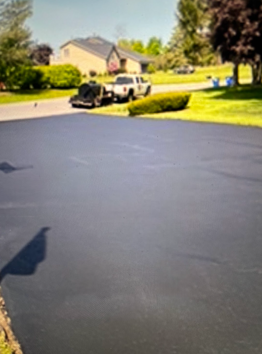 A black car is parked in a driveway next to a house.