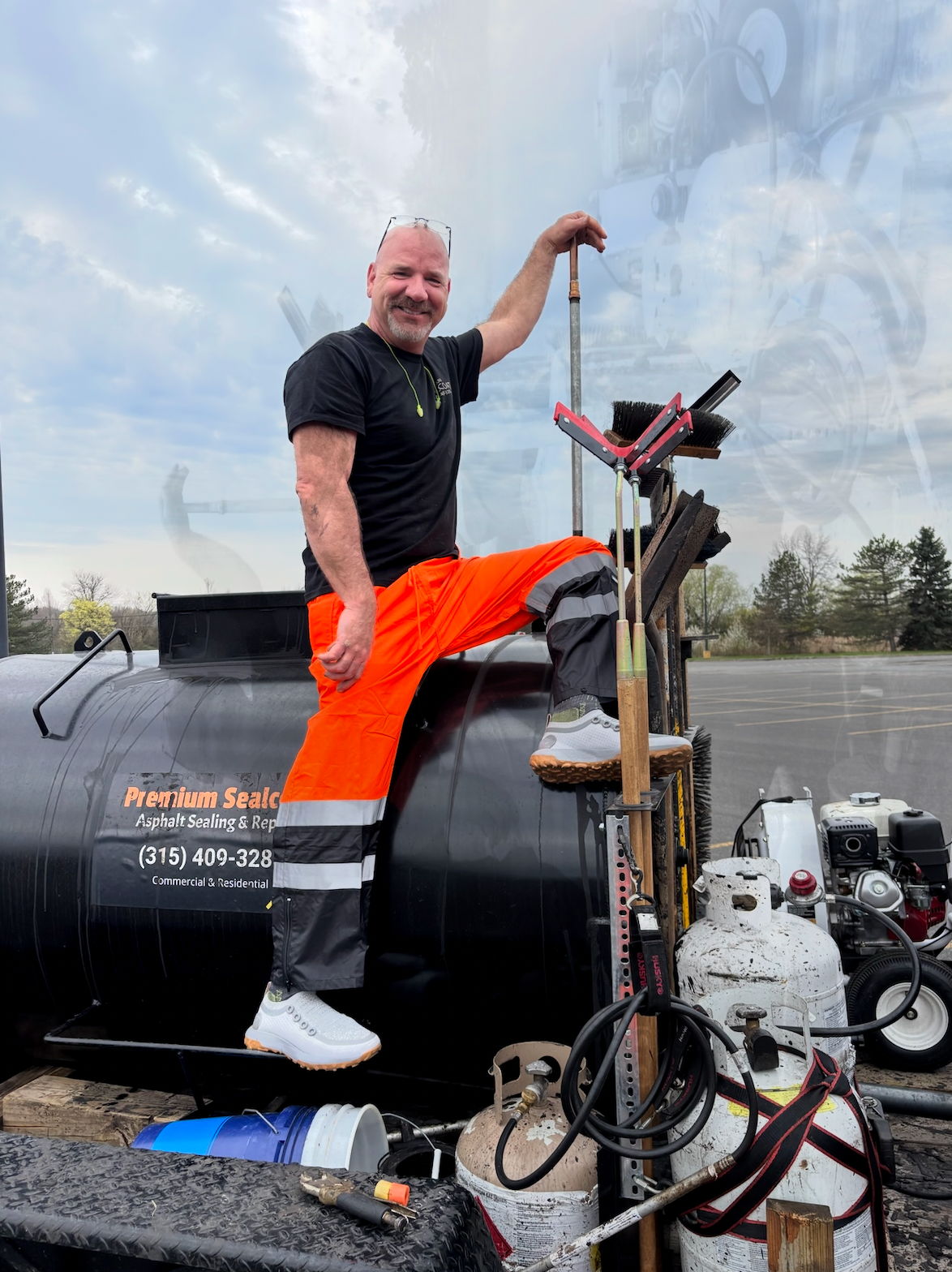 A man in orange pants is sitting on top of a black tank.