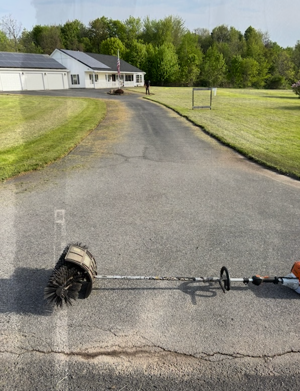 A lawn mower is sitting on the side of a road next to a house.