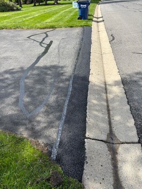 A blue trash can is sitting on the side of the road next to a curb.