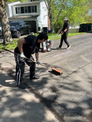 A man is sweeping the sidewalk with a broom.