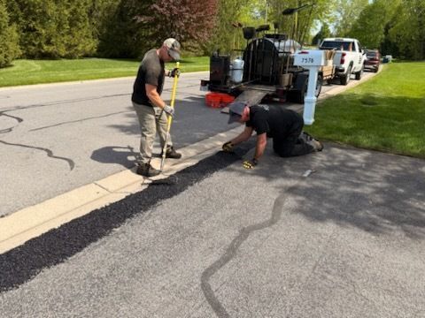 Two men are working on the side of a road.