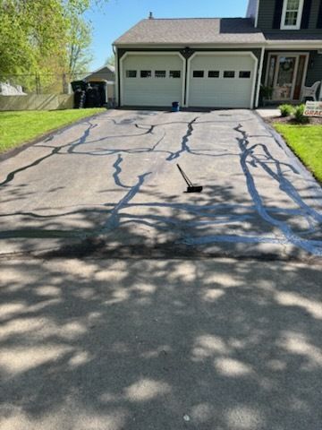 A driveway is being painted in front of a house.