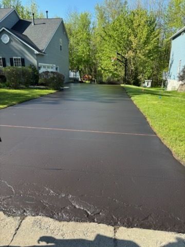 A driveway leading to a house with a lot of grass and trees.