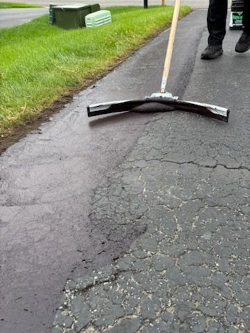 A person is using a broom to clean a driveway.