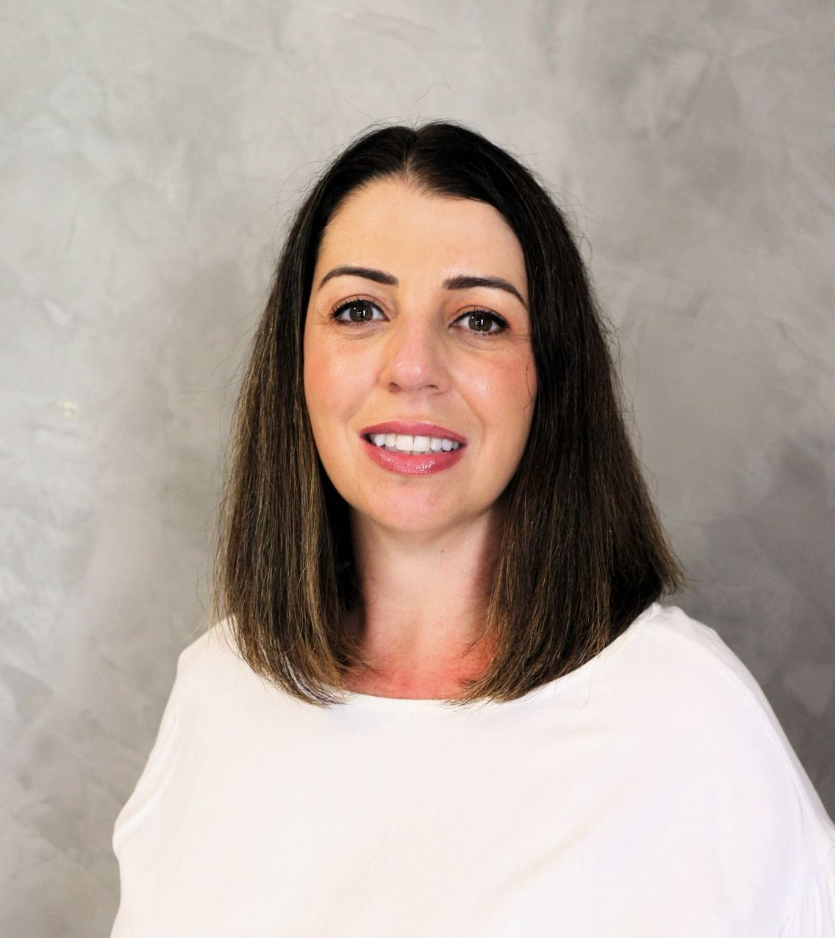 Uma mulher está vestindo uma camisa branca e sorrindo para a câmera.