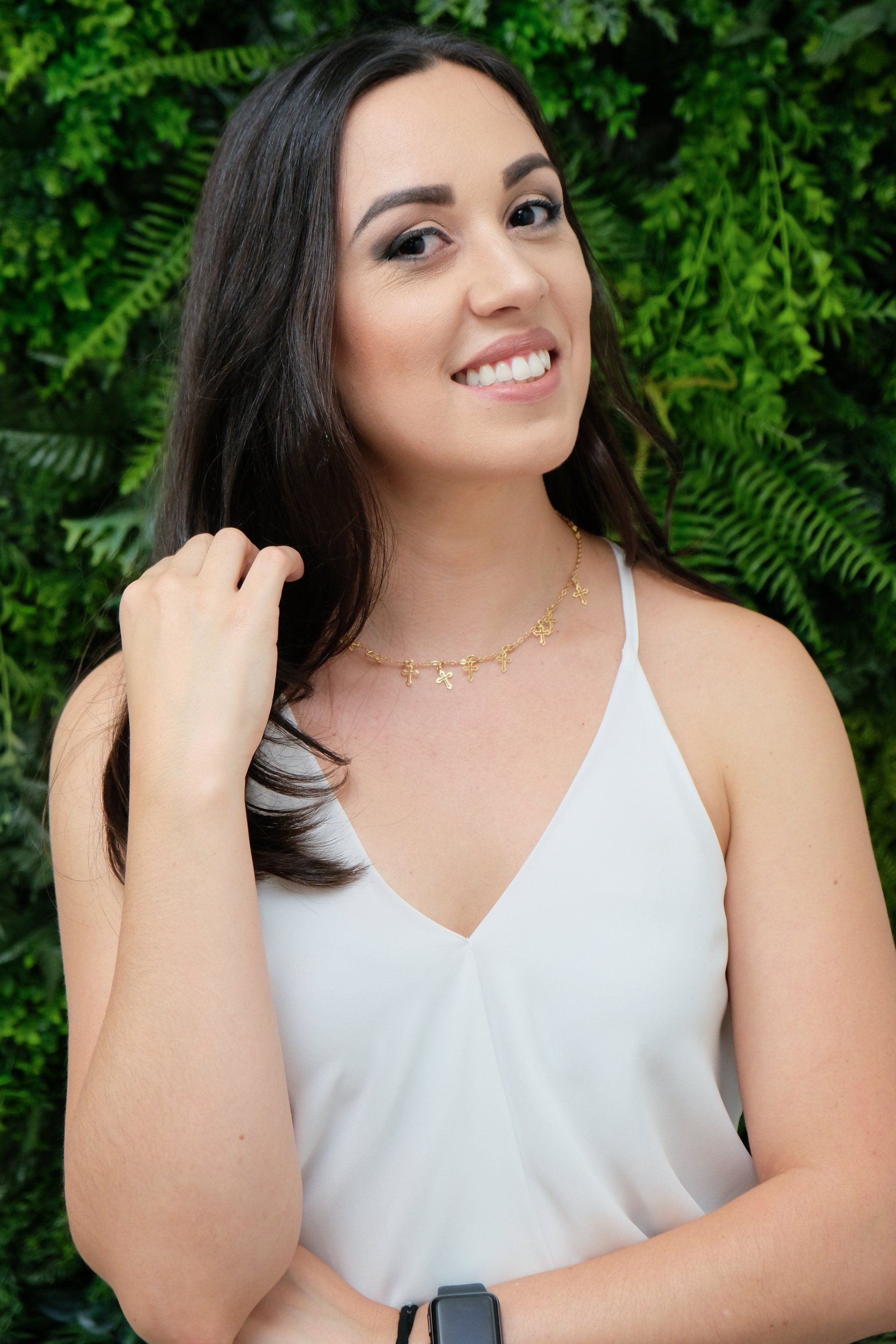 A mulher está vestindo uma regata branca e um colar de ouro.