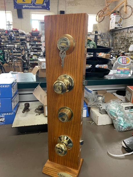 A wooden display of door knobs and keys in a store.