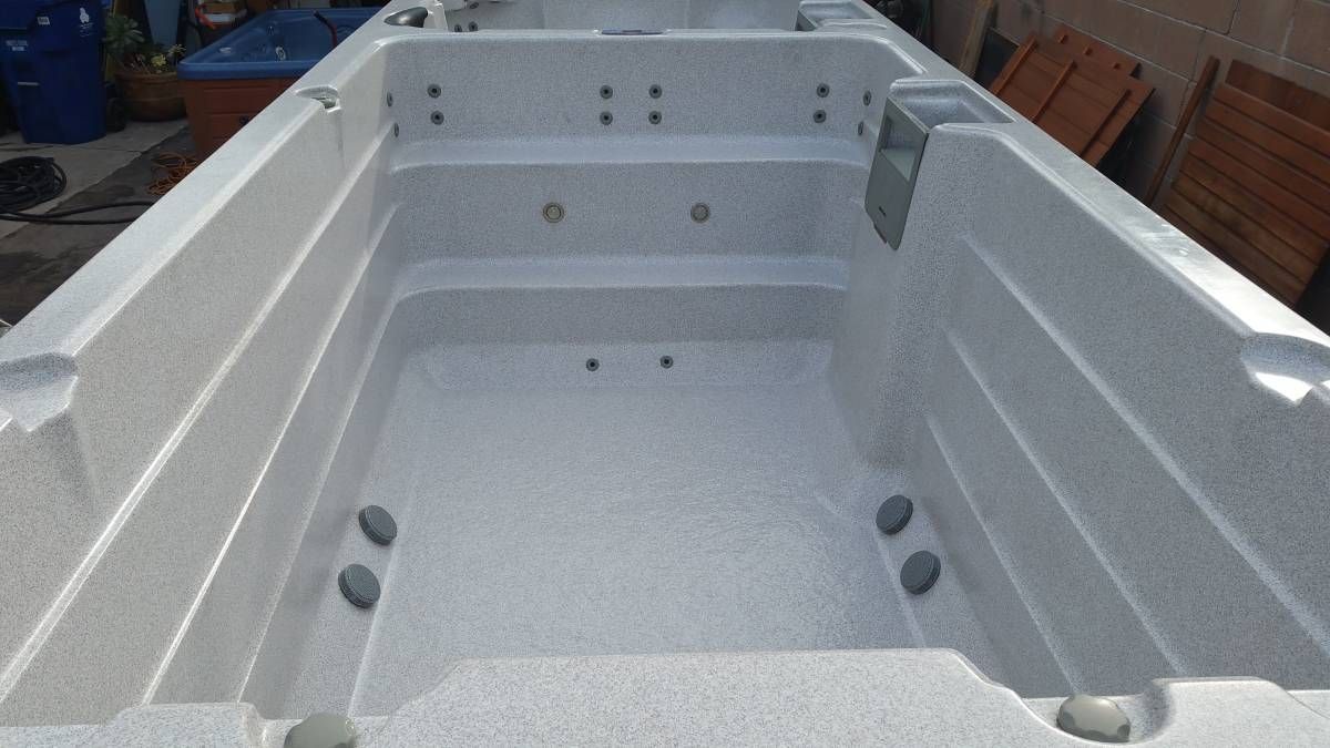 Gray swim spa with jets and steps, outdoors.