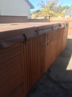 Wooden hot tub with brown cover and siding, outside.