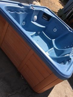 Blue hot tub with brown wooden siding.