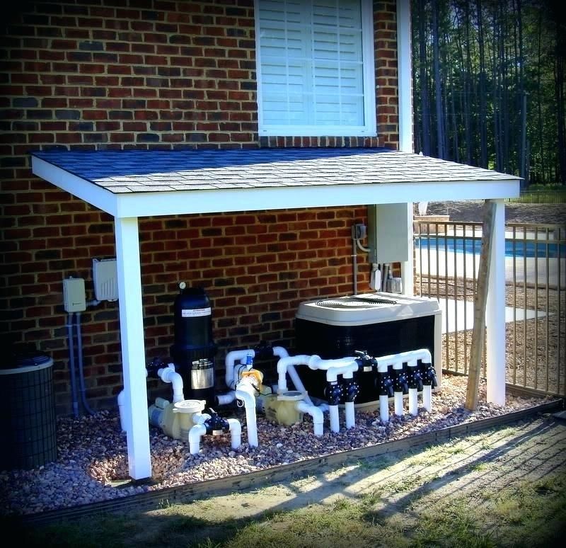Pool equipment under a white-framed shelter next to a brick wall and a fence.