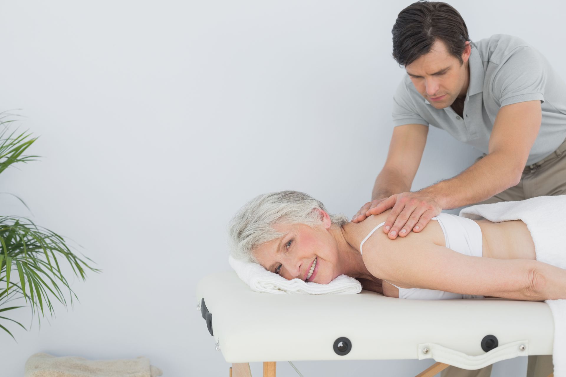 Massage therapist massaging a woman lying face down on a treatment table