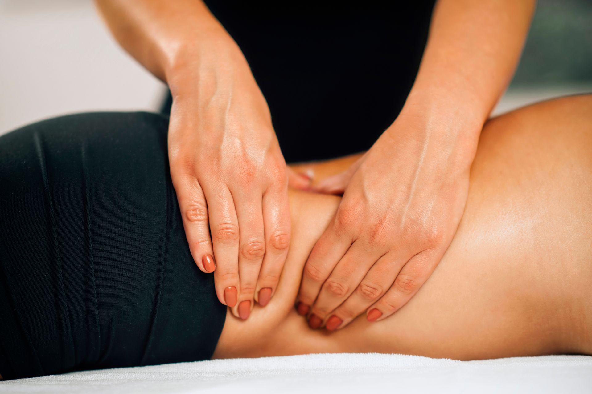 Hands giving a lower-back massage on a person lying face down on a table