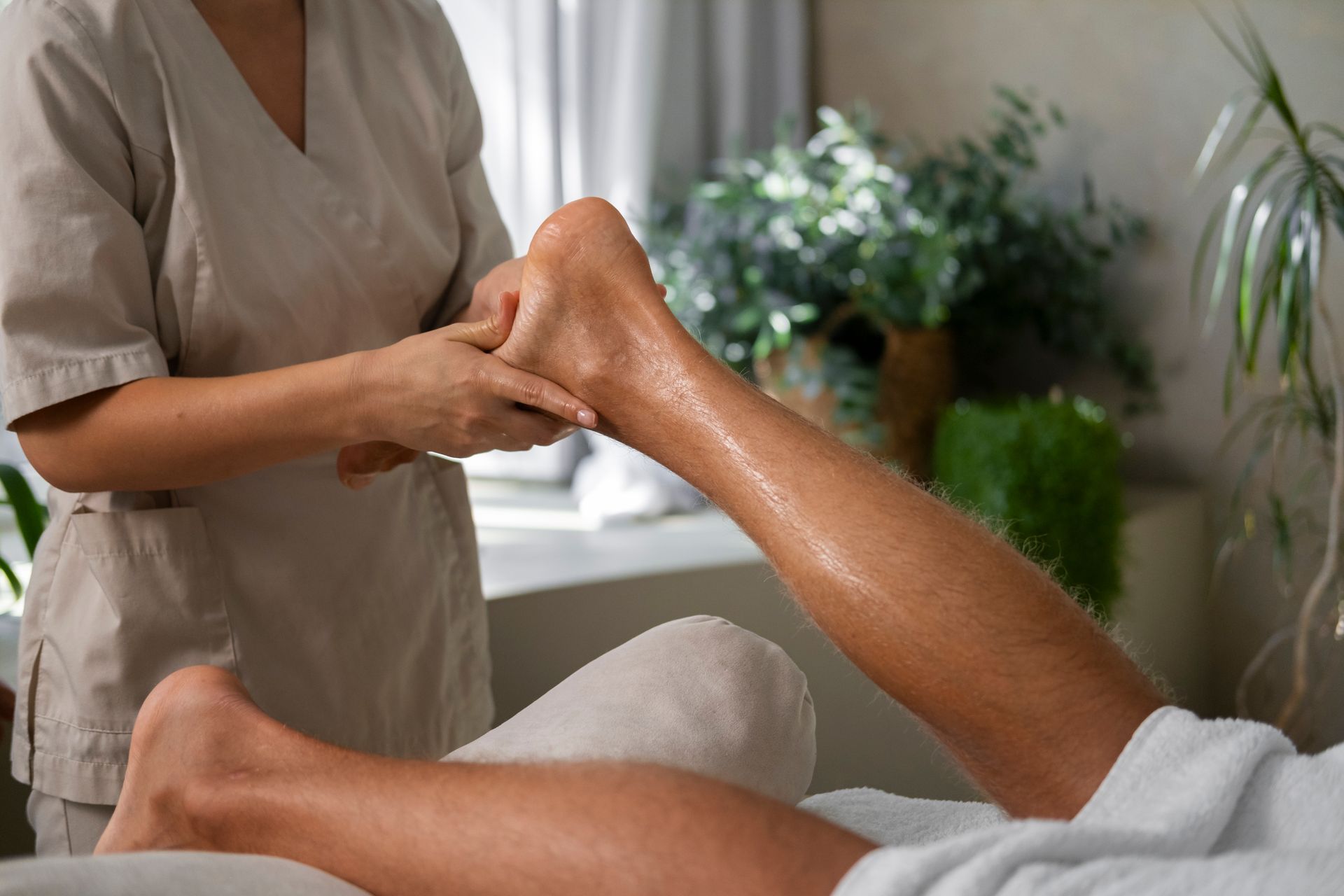Woman giving a foot massage to a person lying on a massage table.