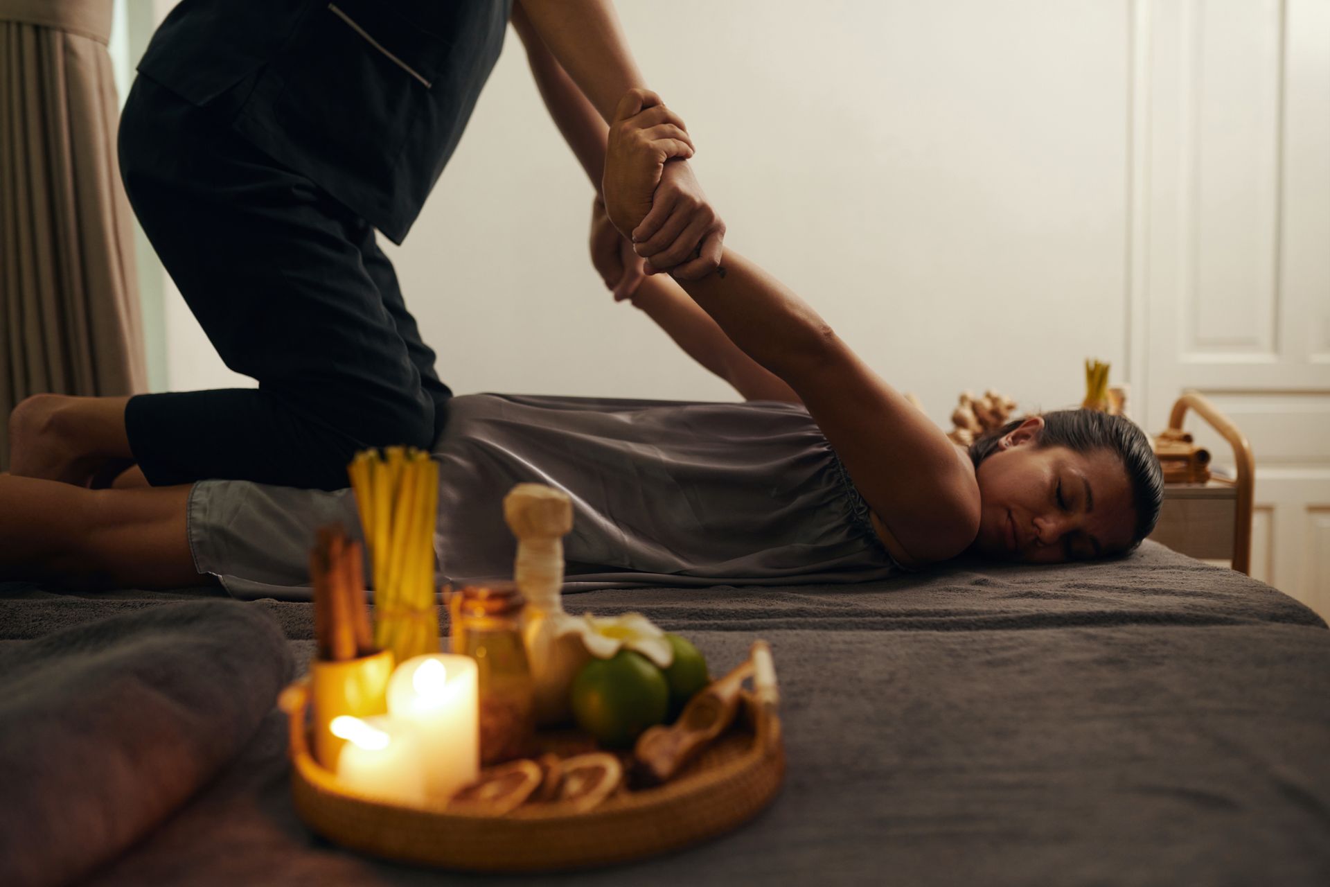 A woman is laying on a bed getting a massage from a massage therapist.