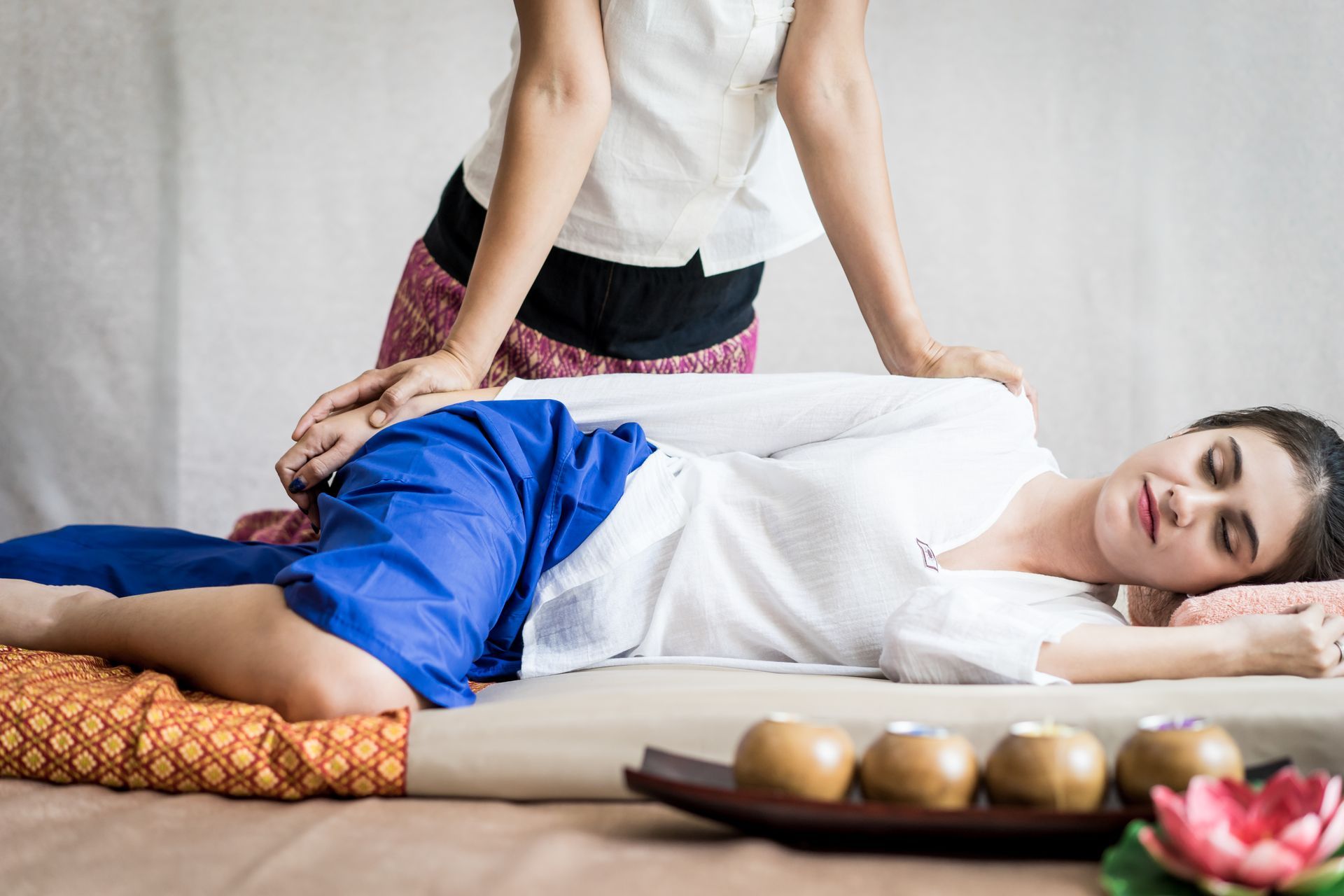 A woman is laying on a bed getting a massage from a massage therapist.