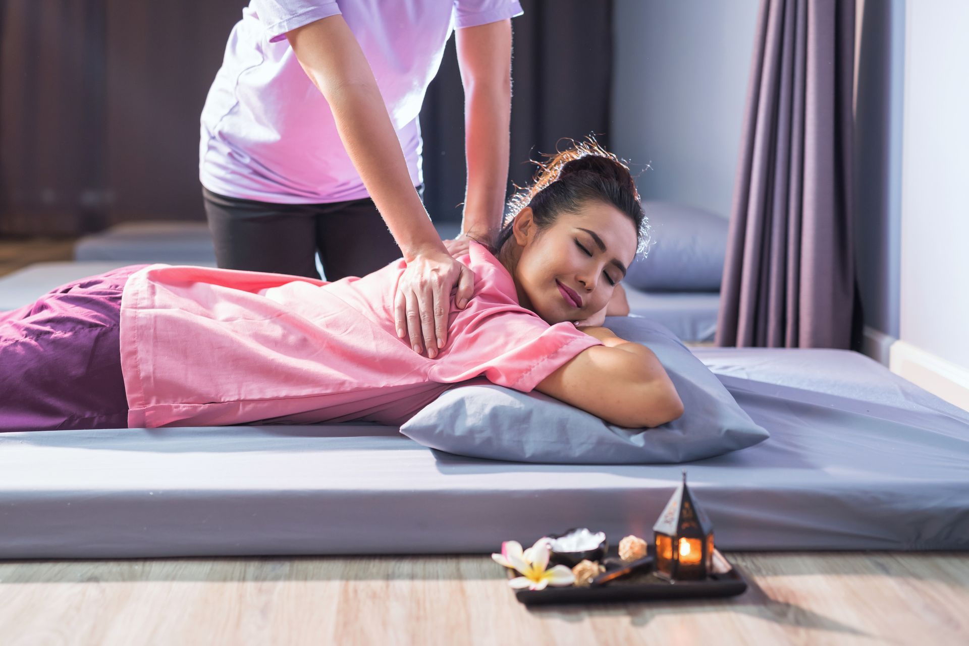 A woman is laying on a bed getting a massage from a massage therapist.
