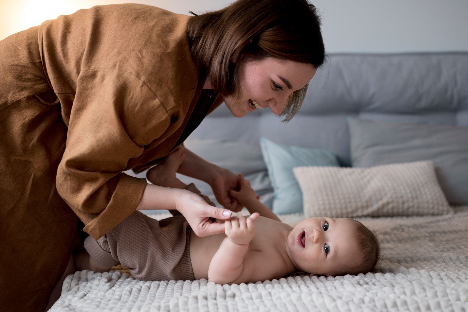 A woman is changing a baby 's diaper on a bed.