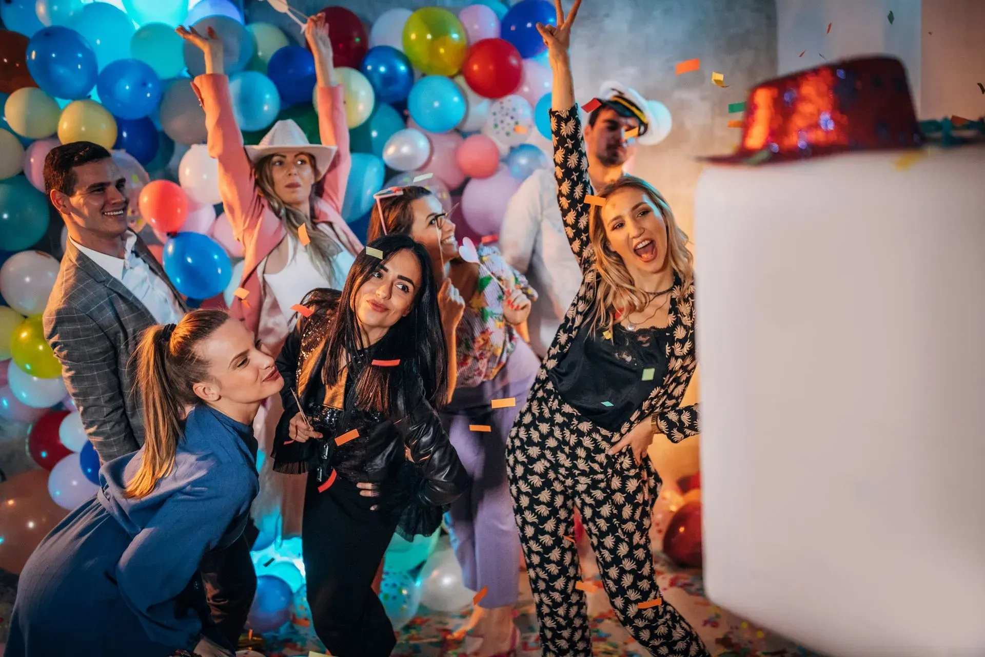 A group of people are posing for a picture in front of a wall of balloons.
