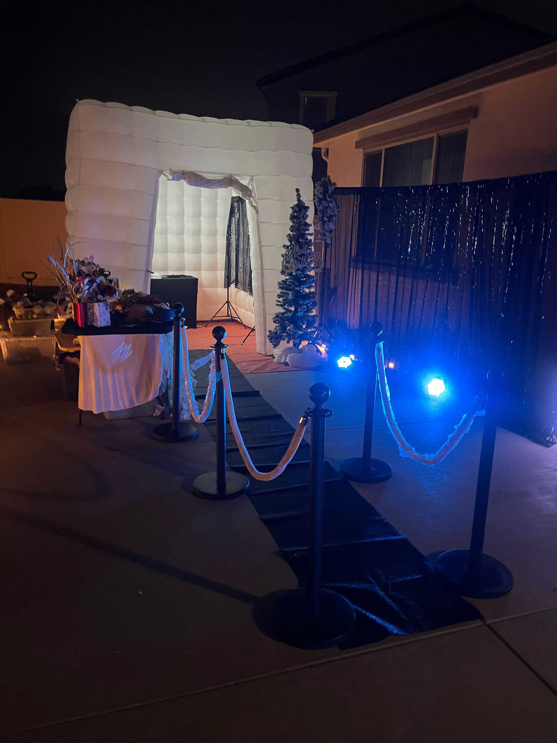 A photo booth is lit up at night with a christmas tree in the background.
