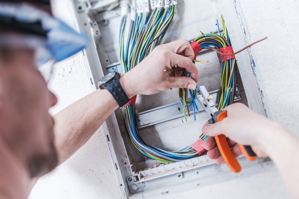Electrician Using Wire Strippers on A Bundle of Colourful Wires — Level Electrical & Air In Taminda, NSW