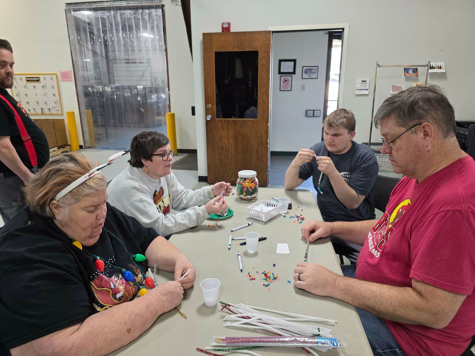 Two people workinGroup of people celebrating in an office; one person is in a wheelchair. They are raising their arms with smiles.g at a computer in an office, one with a prosthetic arm, looking at the screen. Group of people celebrating in an office; one person is in a wheelchair. They are raising their arms with smiles.