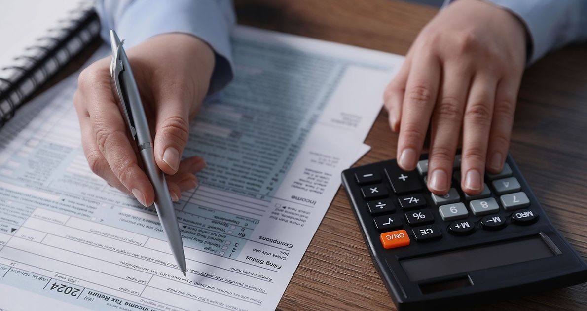 A person is using a calculator and writing on a piece of paper.