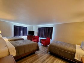 A hotel room with three beds and a television.