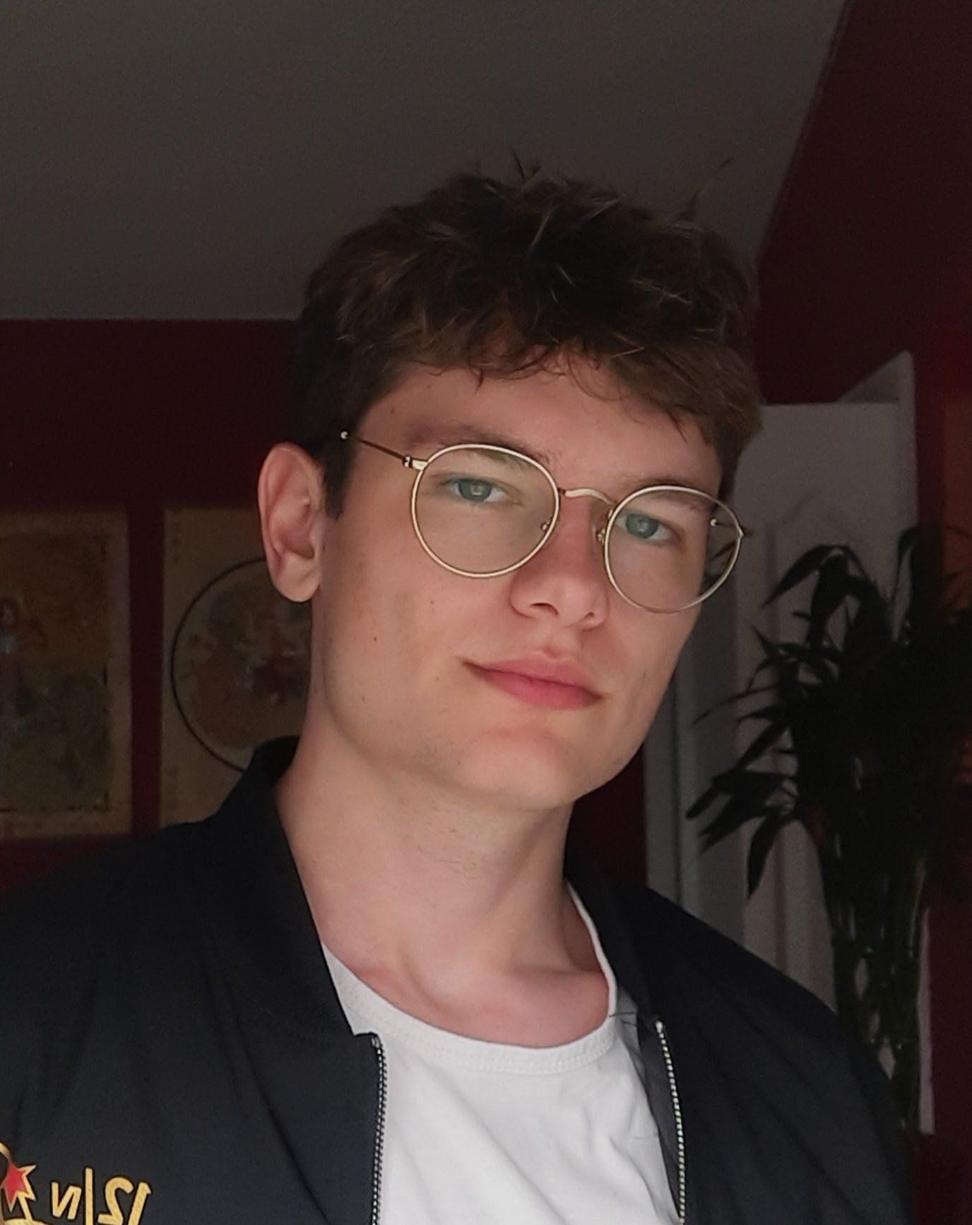 A young man, Alen Avetisov, wearing glasses and a black jacket with the letter s on it