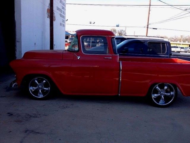 A red truck is parked in front of a white building