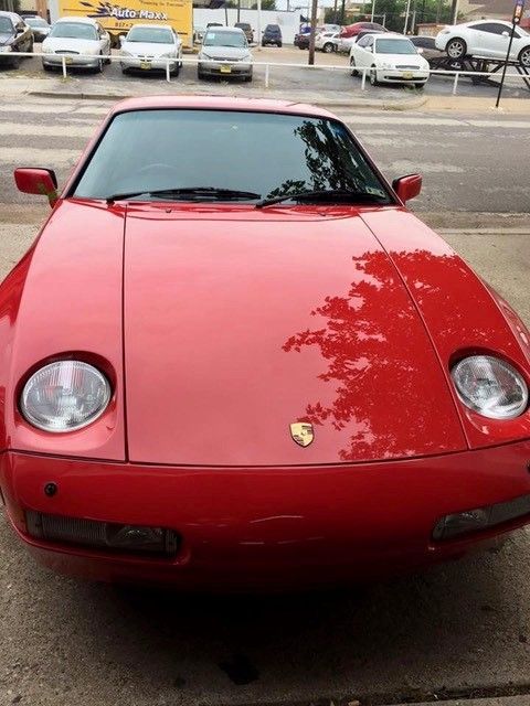 A red sports car is parked in a parking lot
