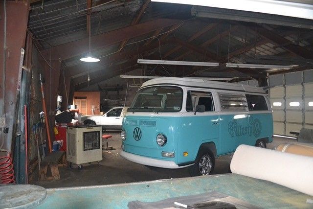 A blue van is parked in a garage next to a boat.