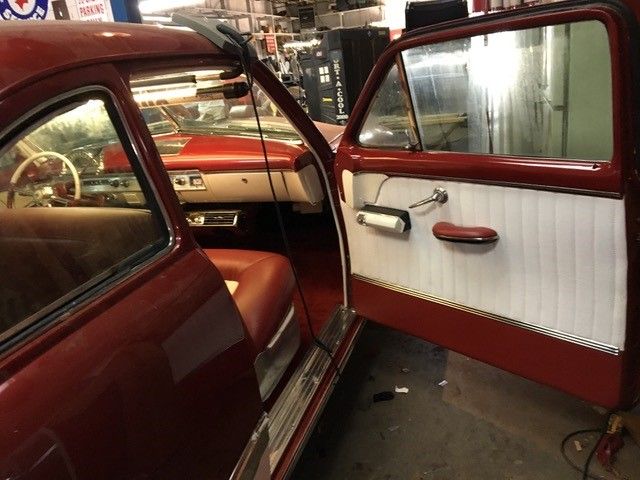 A red car with the door open in a garage