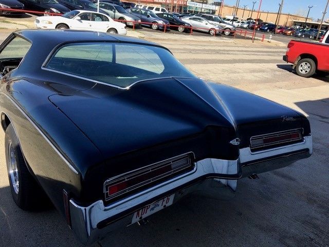 A black car is parked in a parking lot next to a red truck