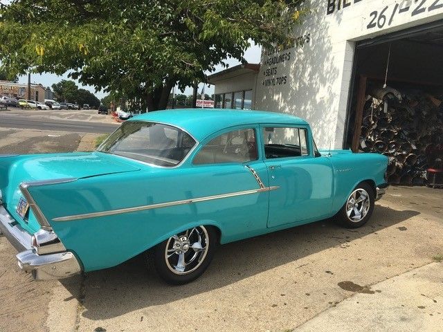 A blue car is parked in front of a building that says 26/22