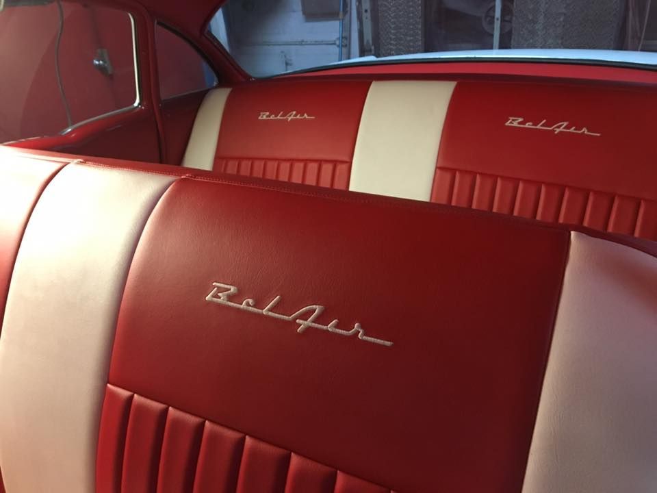 A yellow vintage car is parked in a driveway.