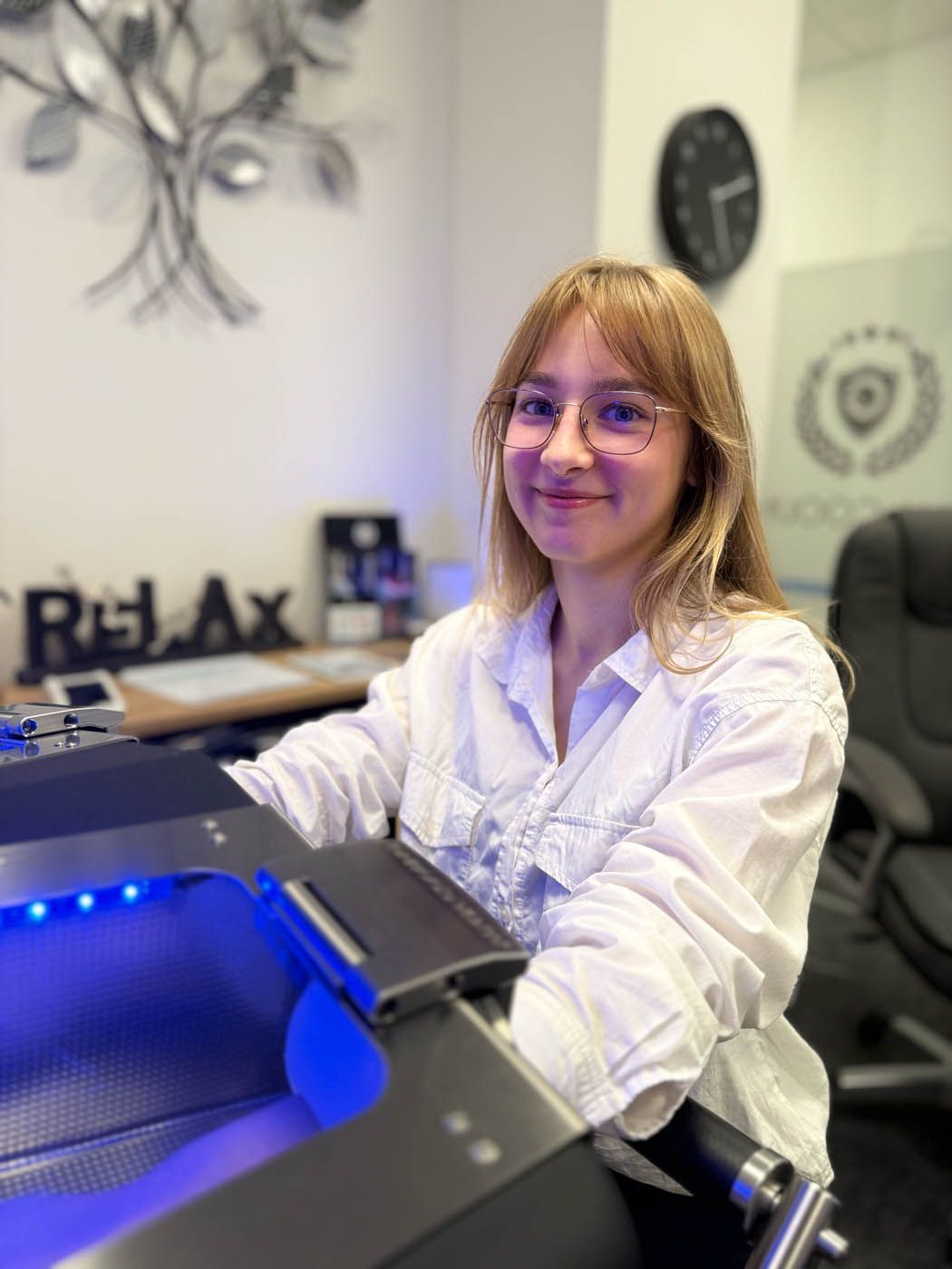 Frau mit Brille lächelt an einem Schreibtisch.
