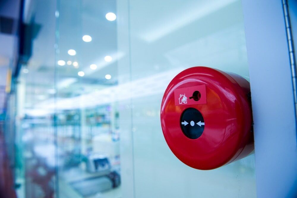 Red Fire Alarm Button on a Glass Wall Indoors — Jendata In Charters Towers, QLD
