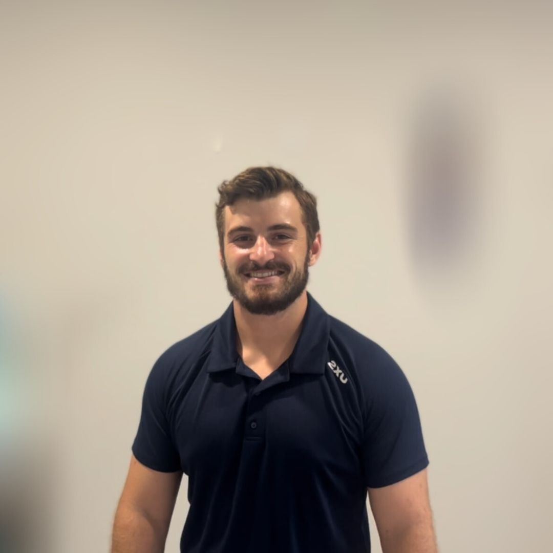 A man with a beard is standing in front of a mirror in a room.