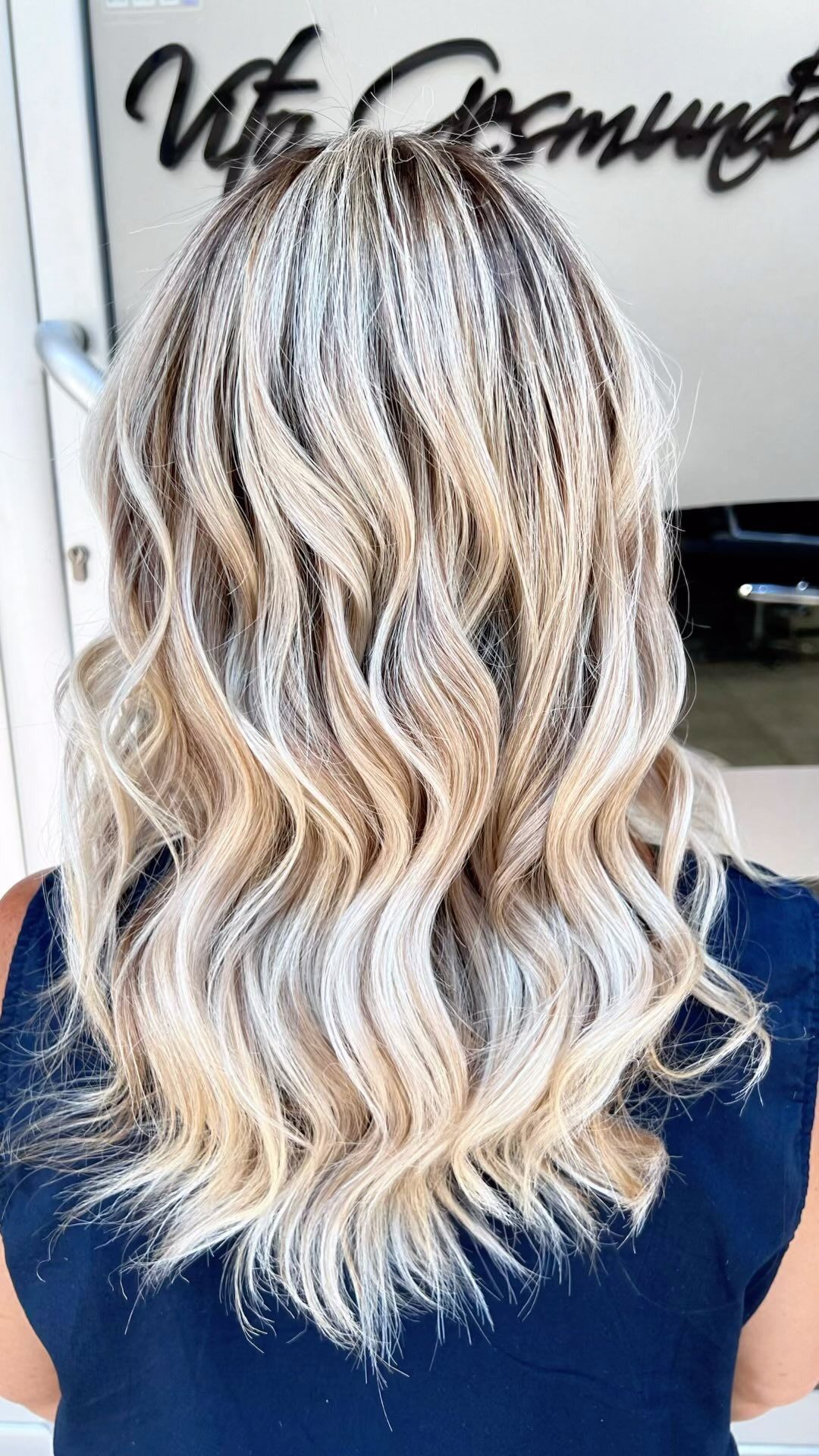 La parte posteriore della testa di una donna con i capelli biondi e una maglietta blu.