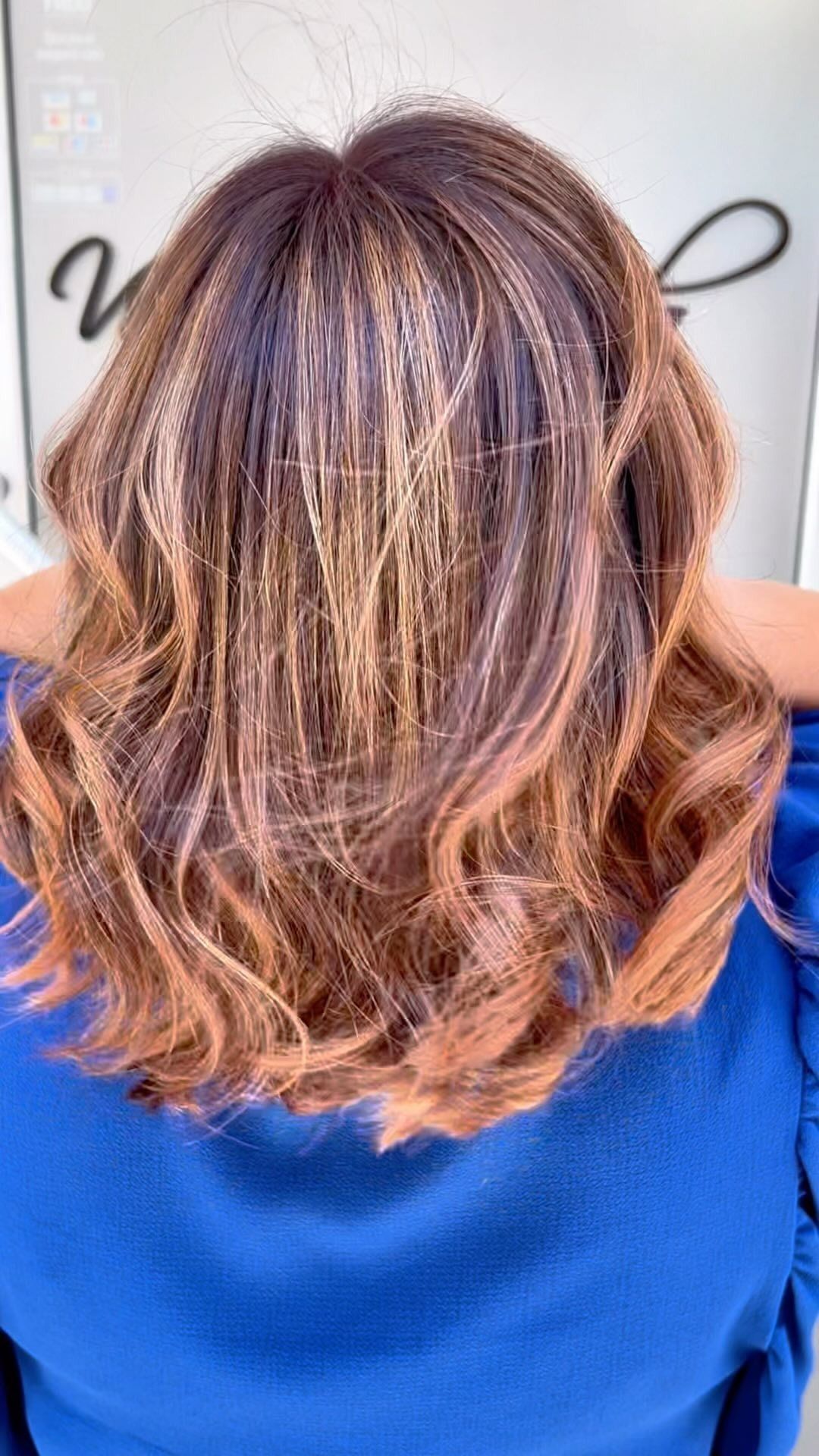 La parte posteriore della testa di una donna con capelli castani e una maglietta blu.