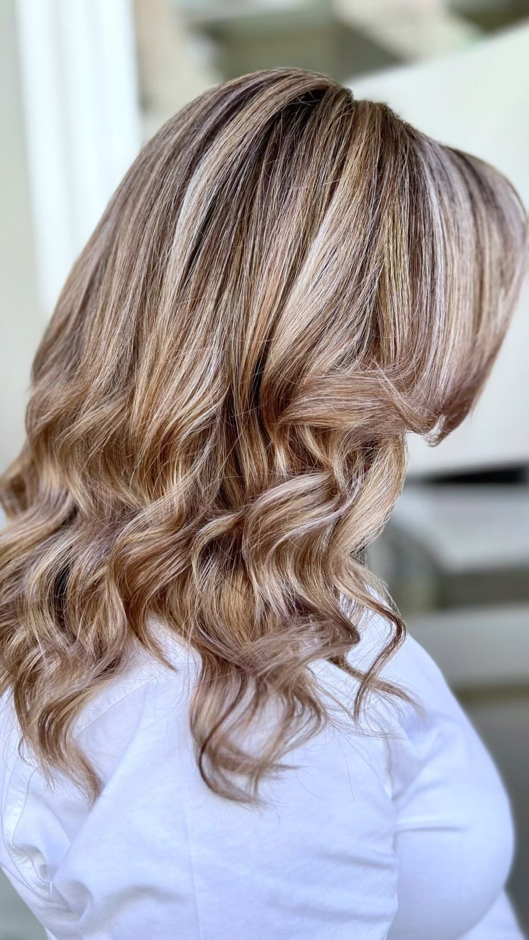 Una donna con lunghi capelli biondi indossa una camicia bianca.